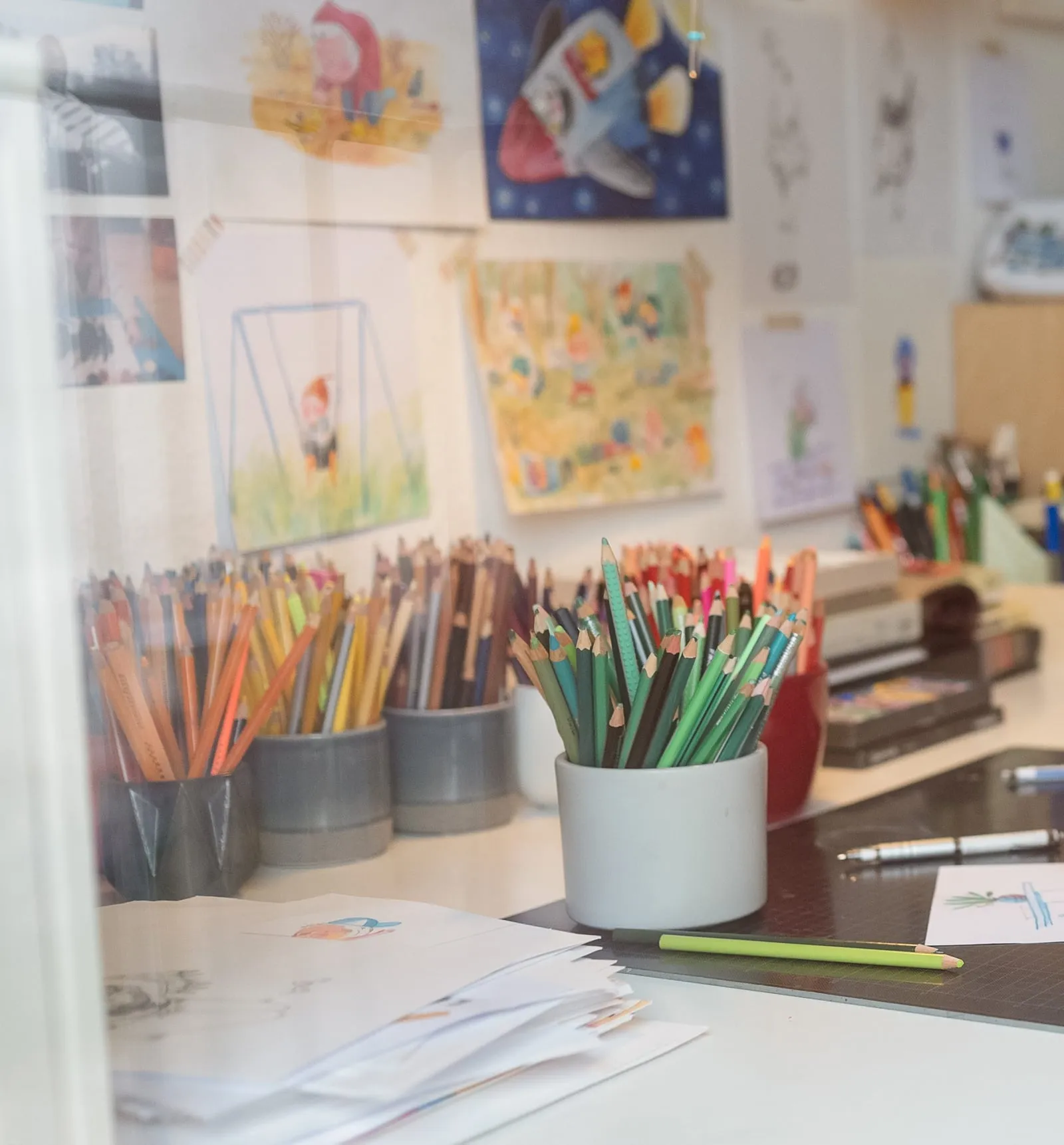 Tiiu Kitsik's studio wall, pinned edge to edge with children's drawings, pots of coloured pencils standing in front of it